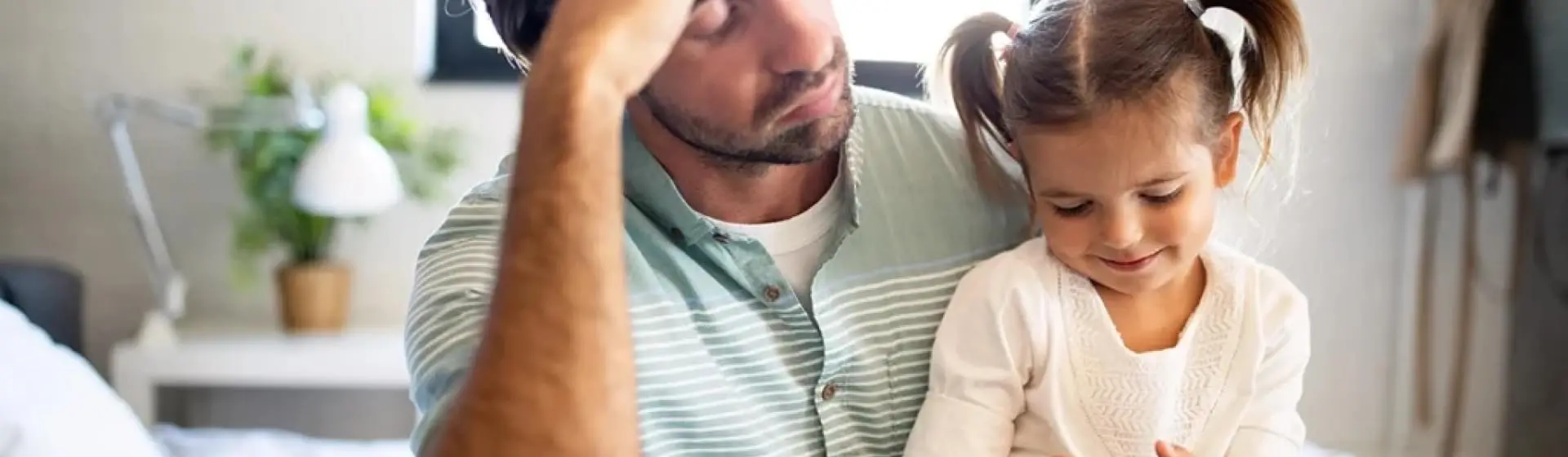 A father sitting down with his daughter on his lap.